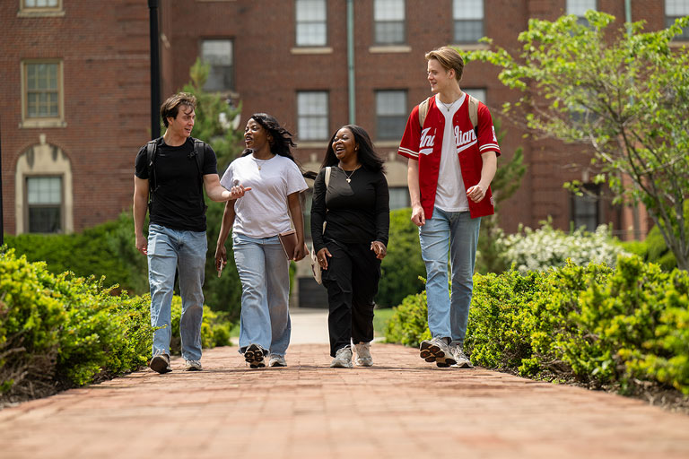 two male and two female students walking and talking on campus