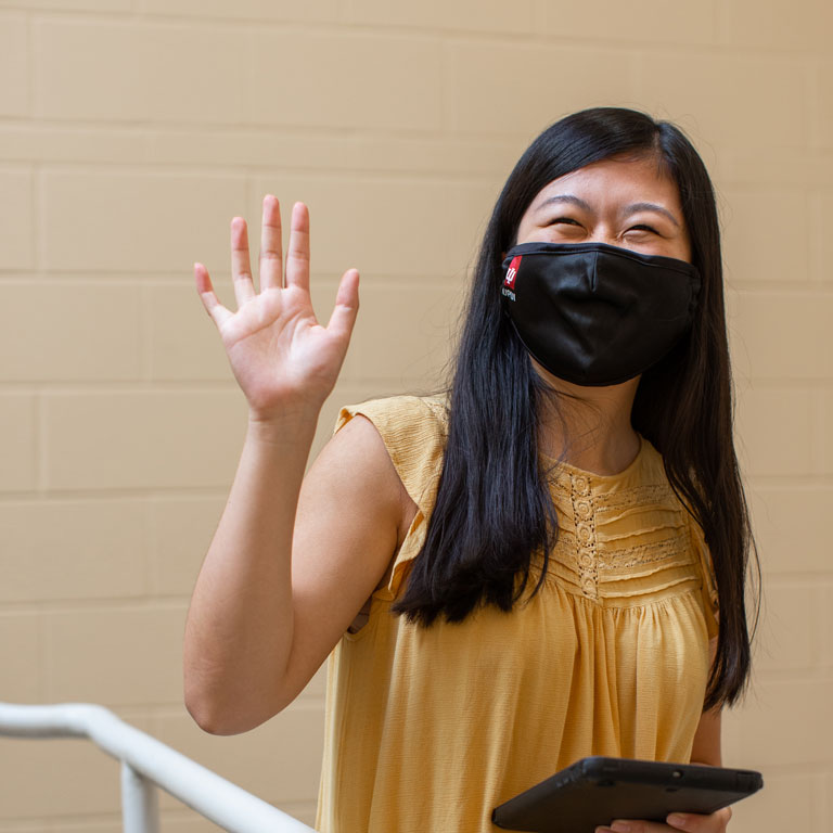 student wearing mask waving