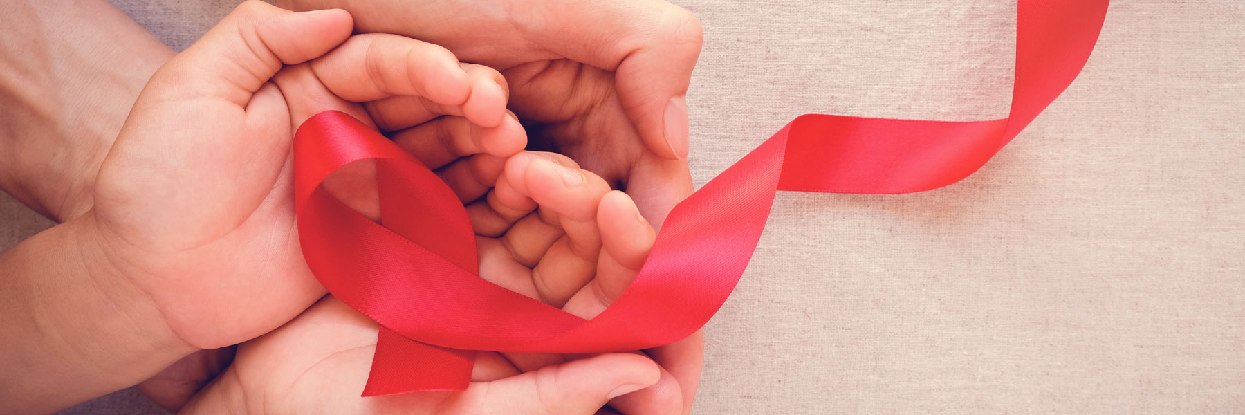 open hands holding a red ribbon